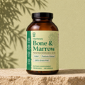 SHIFA Bone & Marrow bottle — halal grass-fed bone and marrow supplement against olive-green plaster