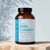 SHIFA Complete bottle — halal grass-fed four-organ supplement against powder-blue plaster